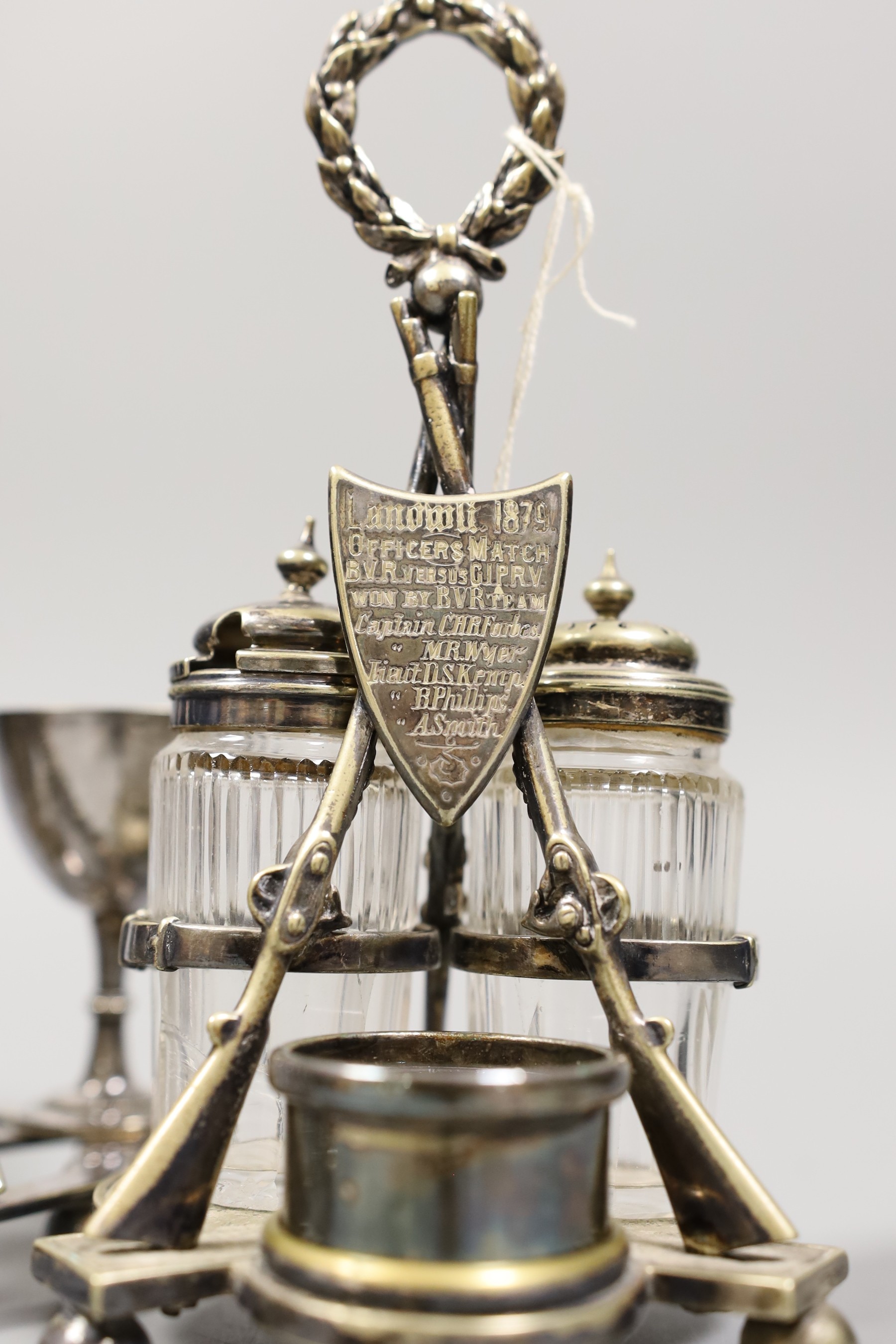 Two plated rifle trophies: toastrack and cruet set, tallest 20cm